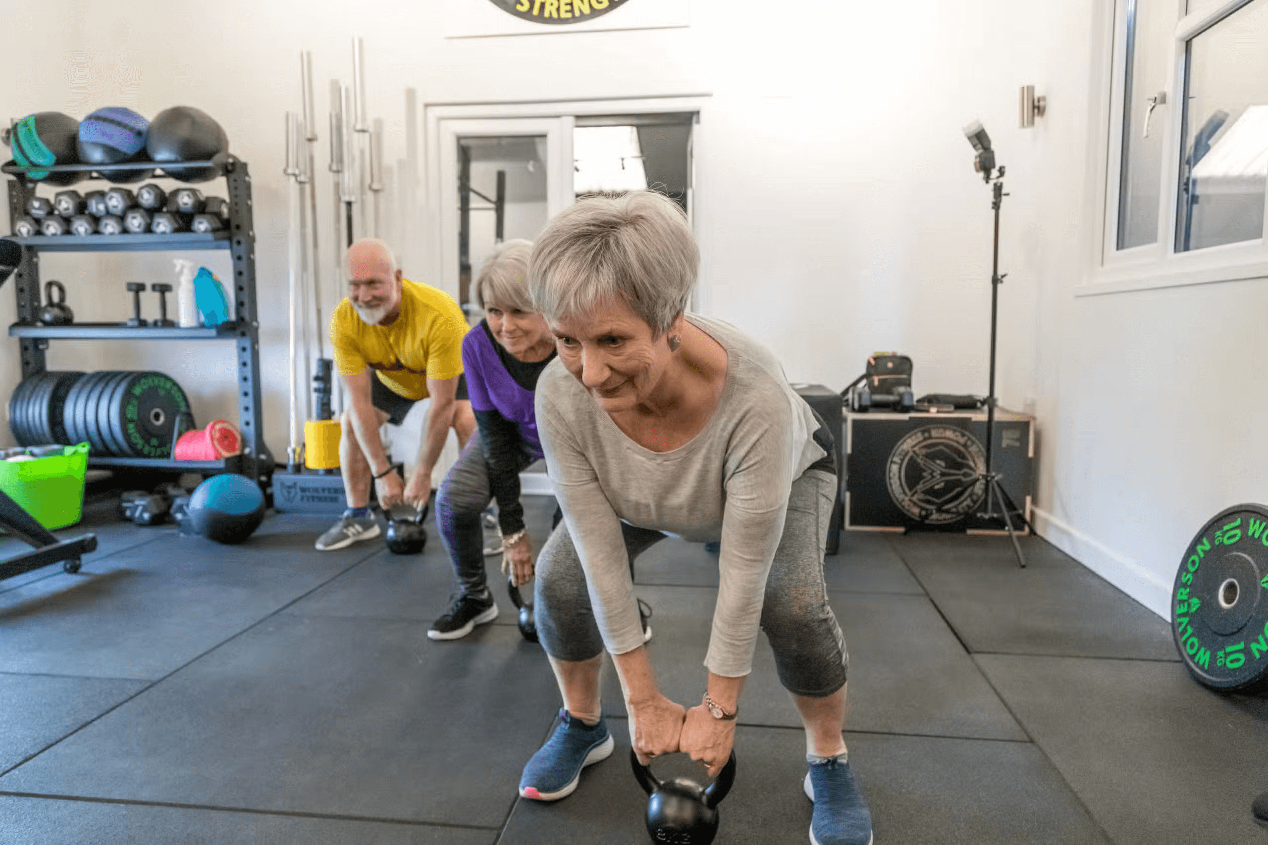 Adults taking part in a kettlebell strength class in a gym.