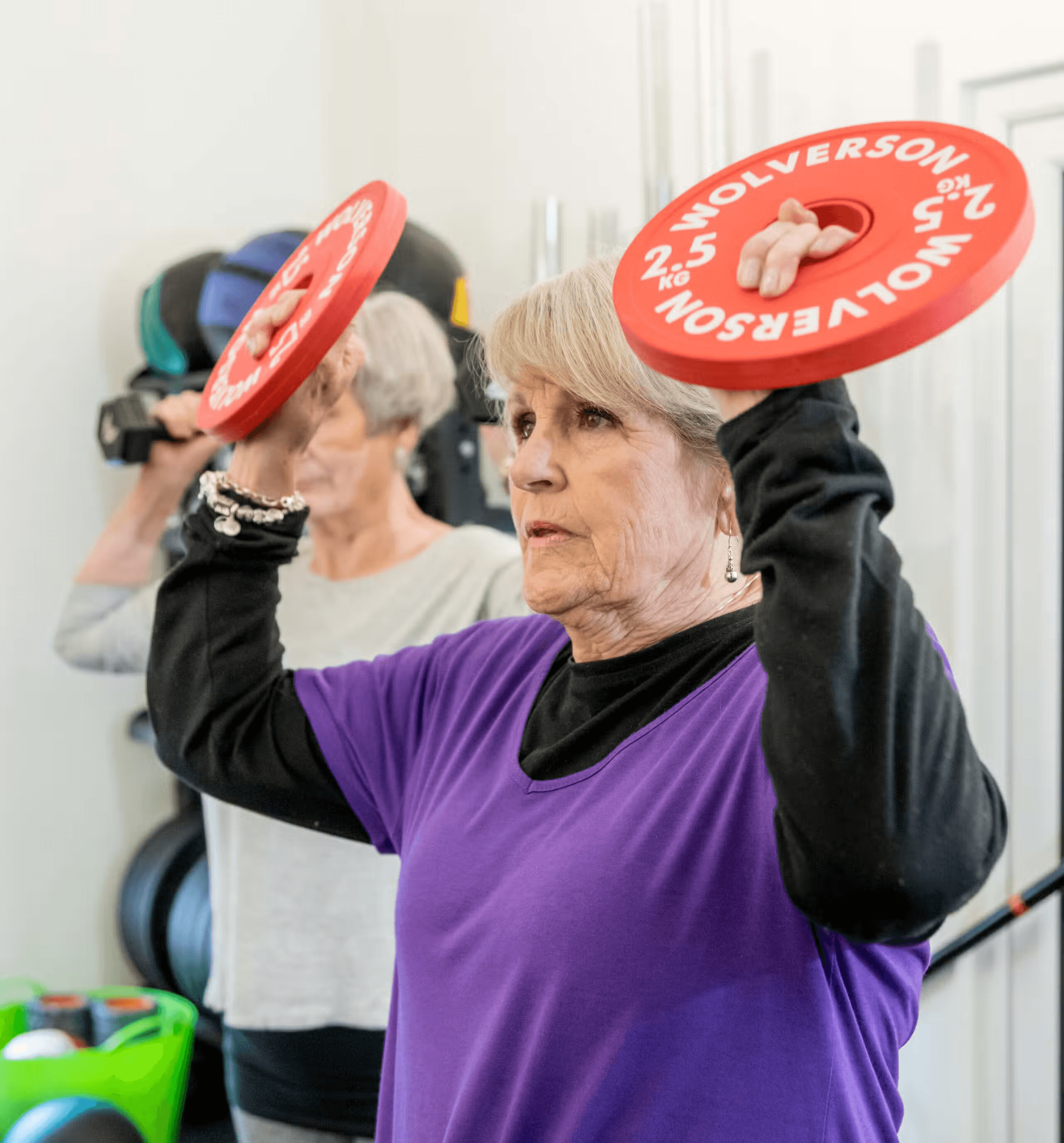 Women lifting weight plates during a strength training class.